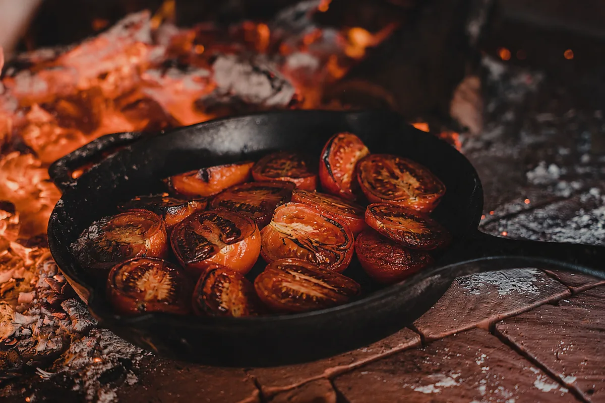 Roasted tomatoes in a cast iron skillet resting on the brick counter