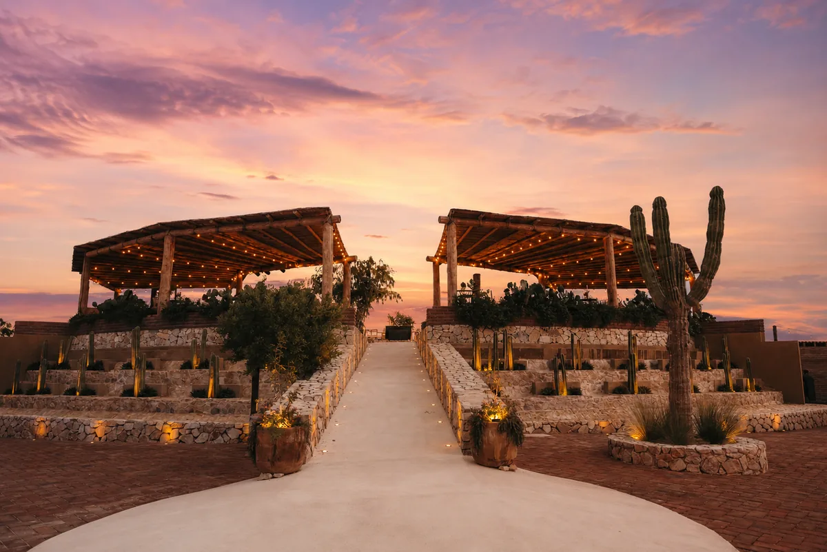 Brick path between two pergolas with cardón cactus and a violet evening sky