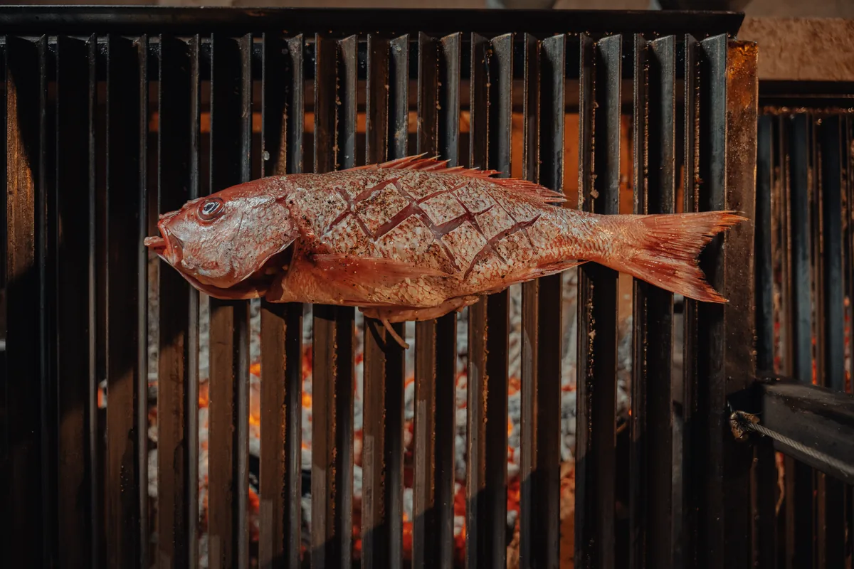 Whole fish grilling over the open fire of the estate kitchen