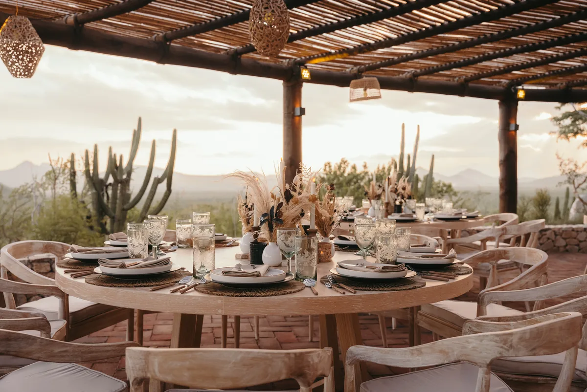 Round tables set under the pergola with pampas grass and cardón cactus behind
