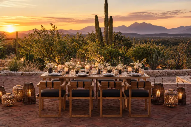 Outdoor table with lanterns among the cactus as the sun sets behind the mountains