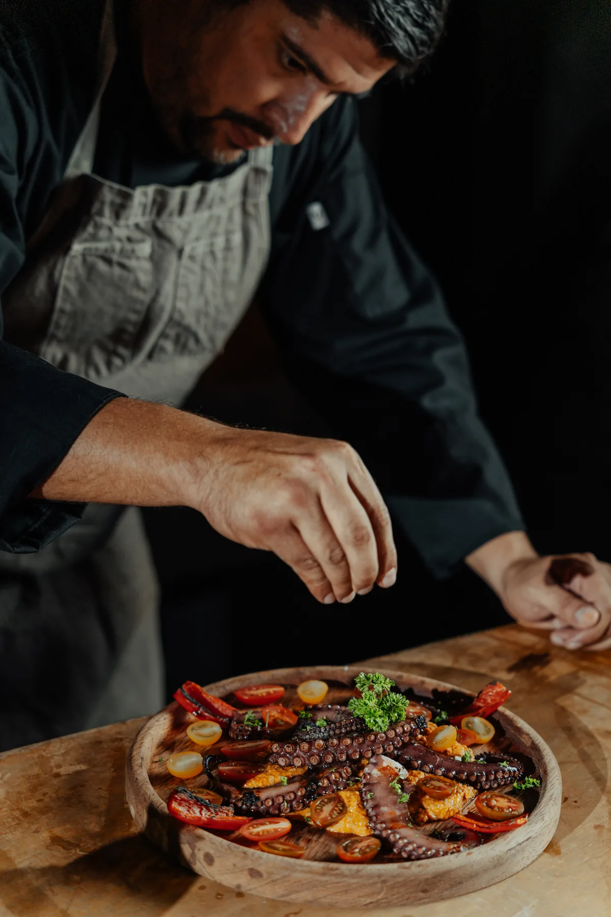 The chef finishing a plate of octopus and vegetables in the estate kitchen