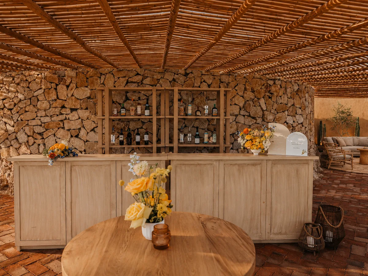 Wooden bar set against a granite stone wall beneath the woven ceiling