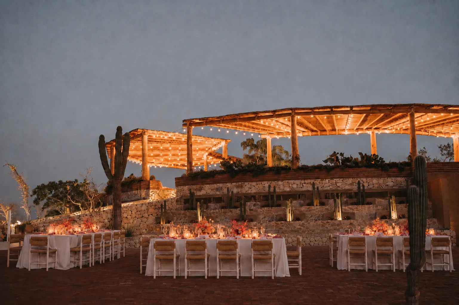 Terraced dining area lit at dusk with cactus along the stone walls