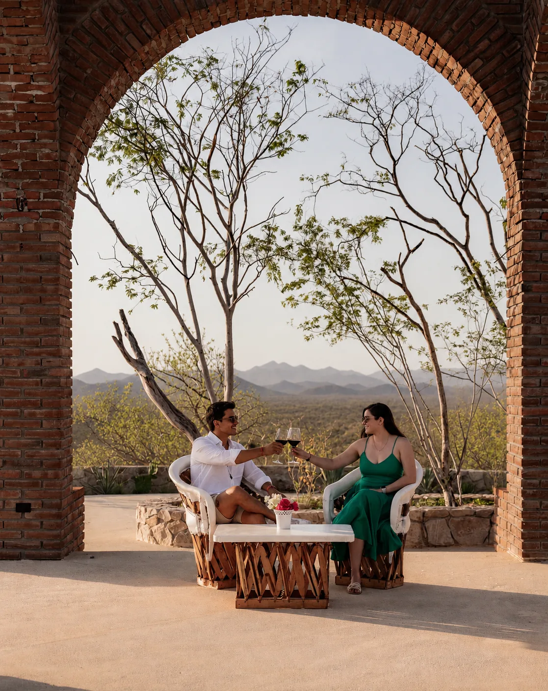 A couple toasting on the terrace beneath the brick arch, with the desert beyond