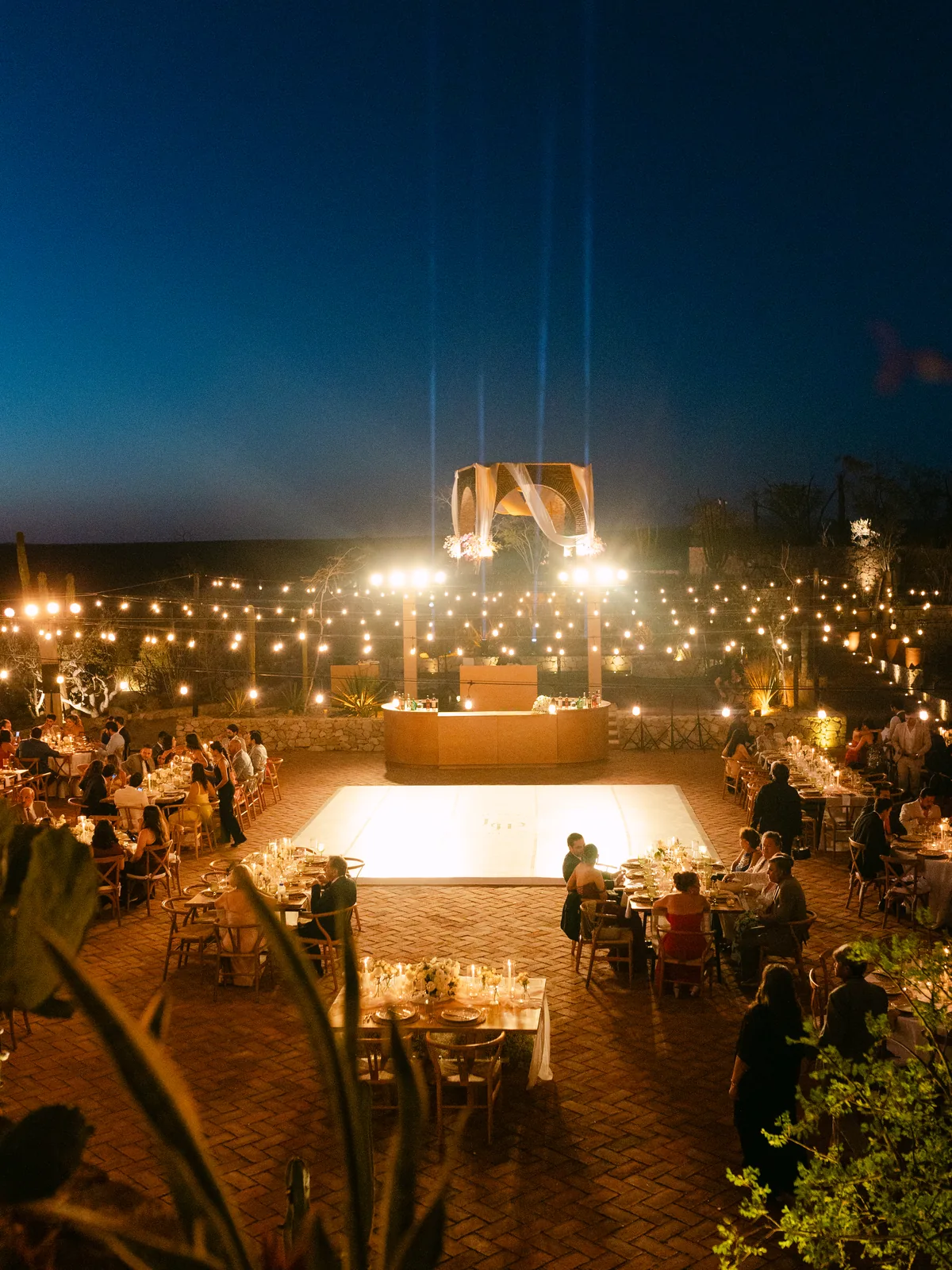 The estate at night with string lights strung above the dance floor and tables