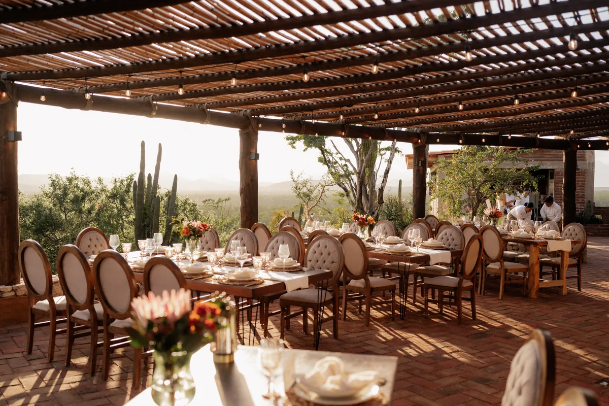 Dining tables under the pergola with the desert and cactus beyond