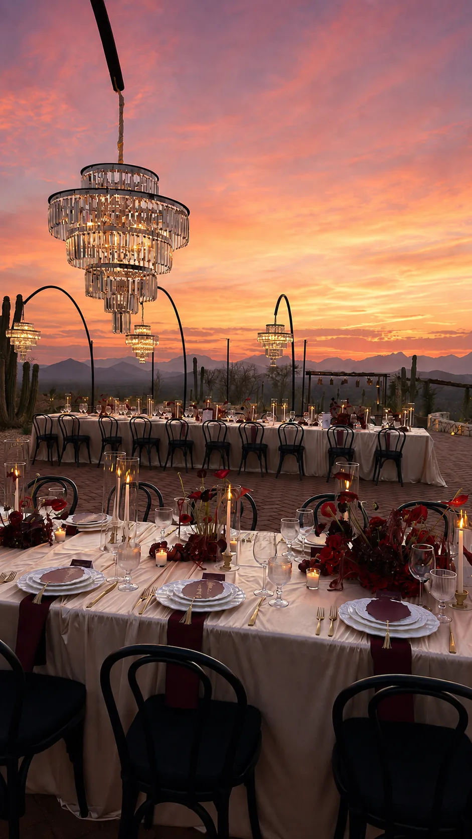 Tables set beneath a chandelier with cardón cactus and a pink evening sky