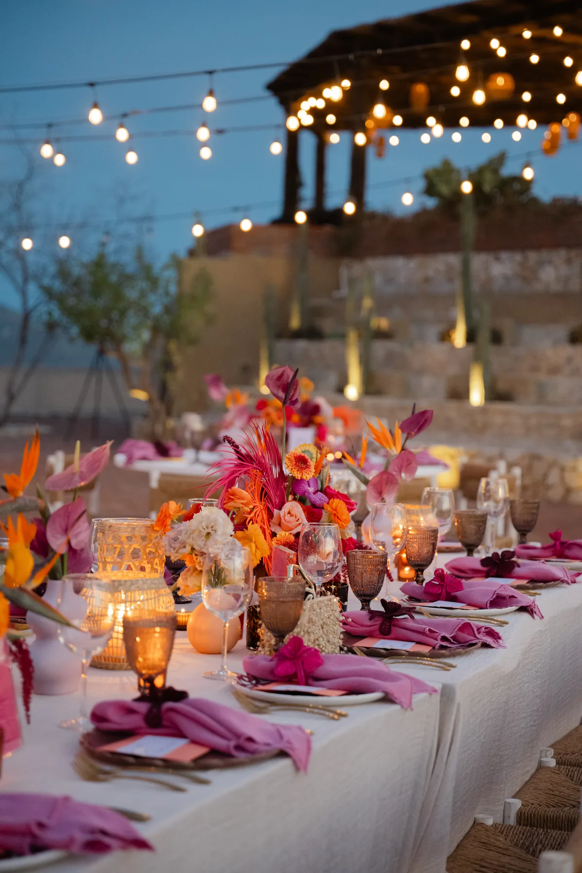 Table dressed in pink and orange florals with candles on the terrace