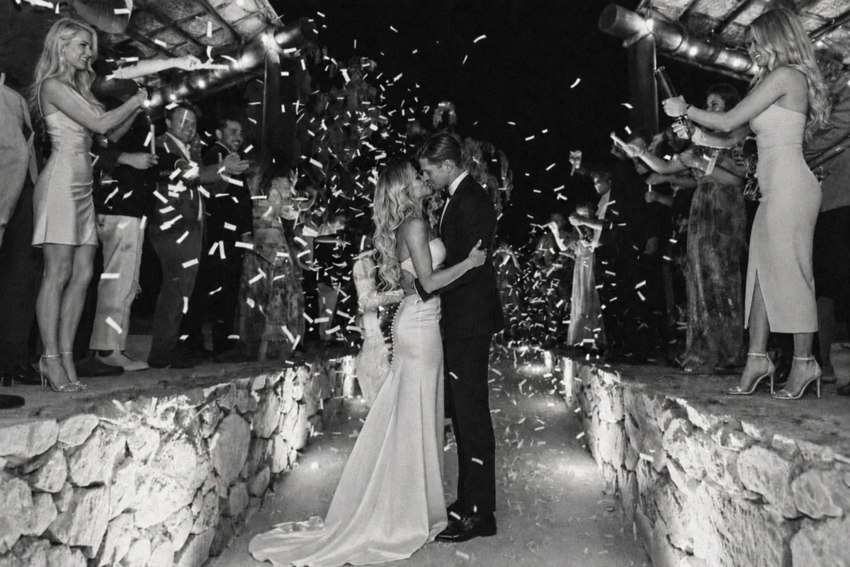 Bride and groom in a shower of confetti as guests celebrate around them