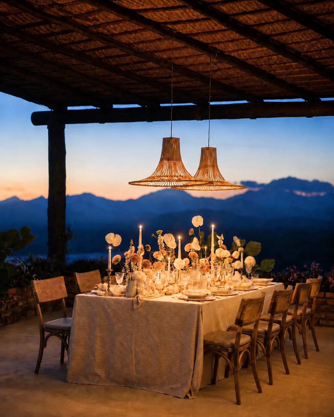 Table set under the pergola with woven lamps and candles at dusk